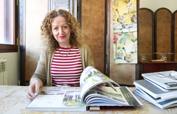 Imagen de retrato de Sonia Marco sentada en su despacho donde recibe los clientes con un libro de muestras 